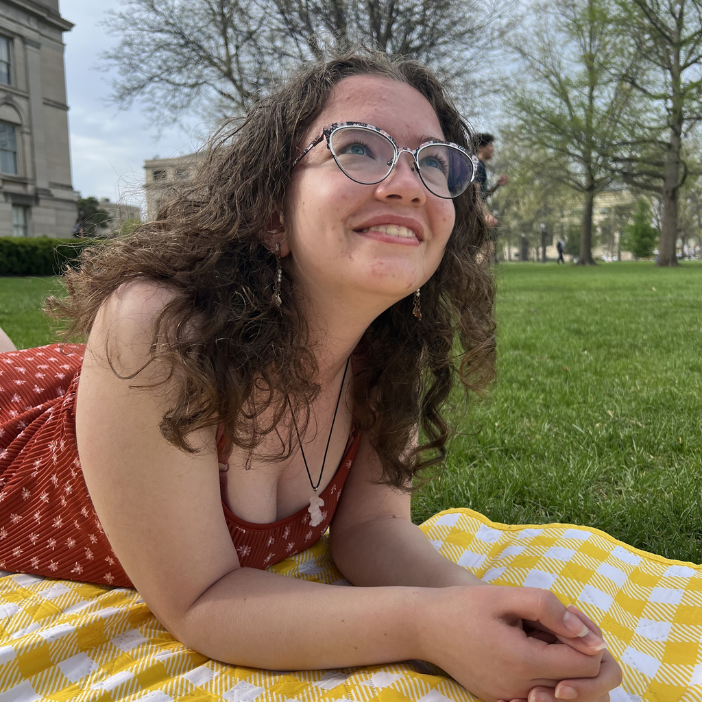 Caitlin posing for a photo on a yellow picnic blanket.