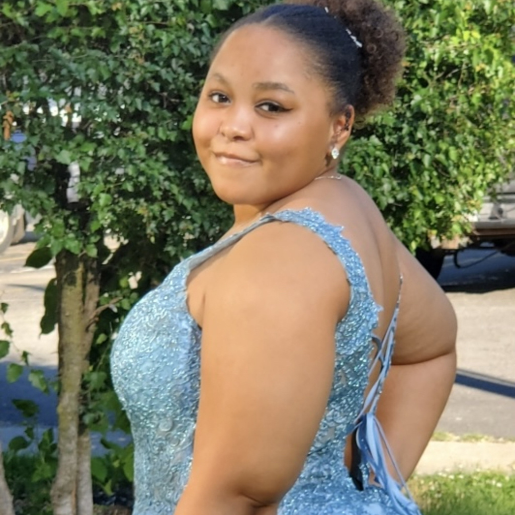 Tatiana in a blue dress in front of a tree. 