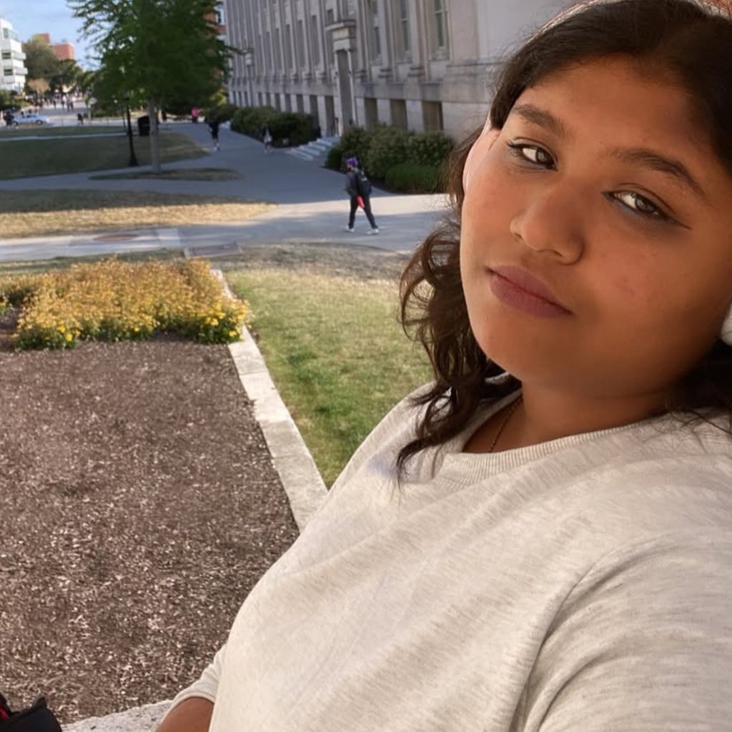 Anupama posing for a selfie in front of a building. 